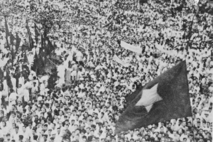 Black and white historical photo of a large crowd gathered, waving Vietnam flags, symbolizing a significant political event.