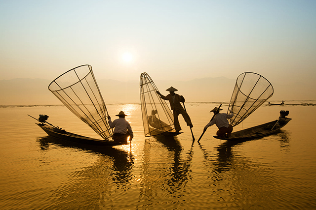 Fishing men catching fish toward the sunset